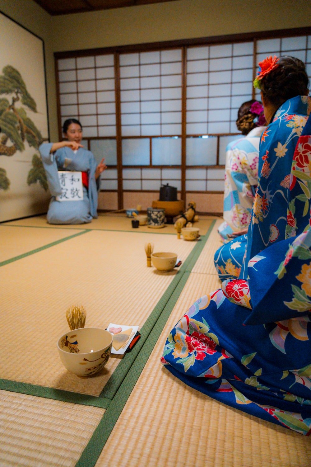 Woman in traditional houmongi kimono participating in authentic Japanese tea ceremony showcasing proper attire for cultural experiences